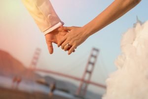 Bride and groom holding hands and Golden Gate Bridge- San Francisco wedding photographers