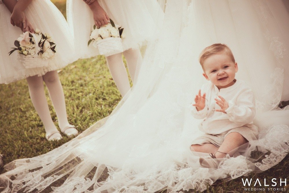 baby sitting on brides dress at wedding